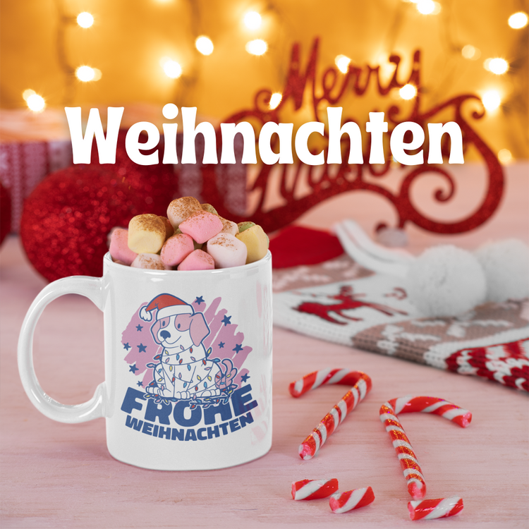 Weihnachtstasse mit Hundemotiv und Spruch "Frohe Weihnachten", gefüllt mit Marshmallows. Im Hintergrund festliche Deko mit Lichtern, Zuckerstangen und Weihnachtsaccessoires